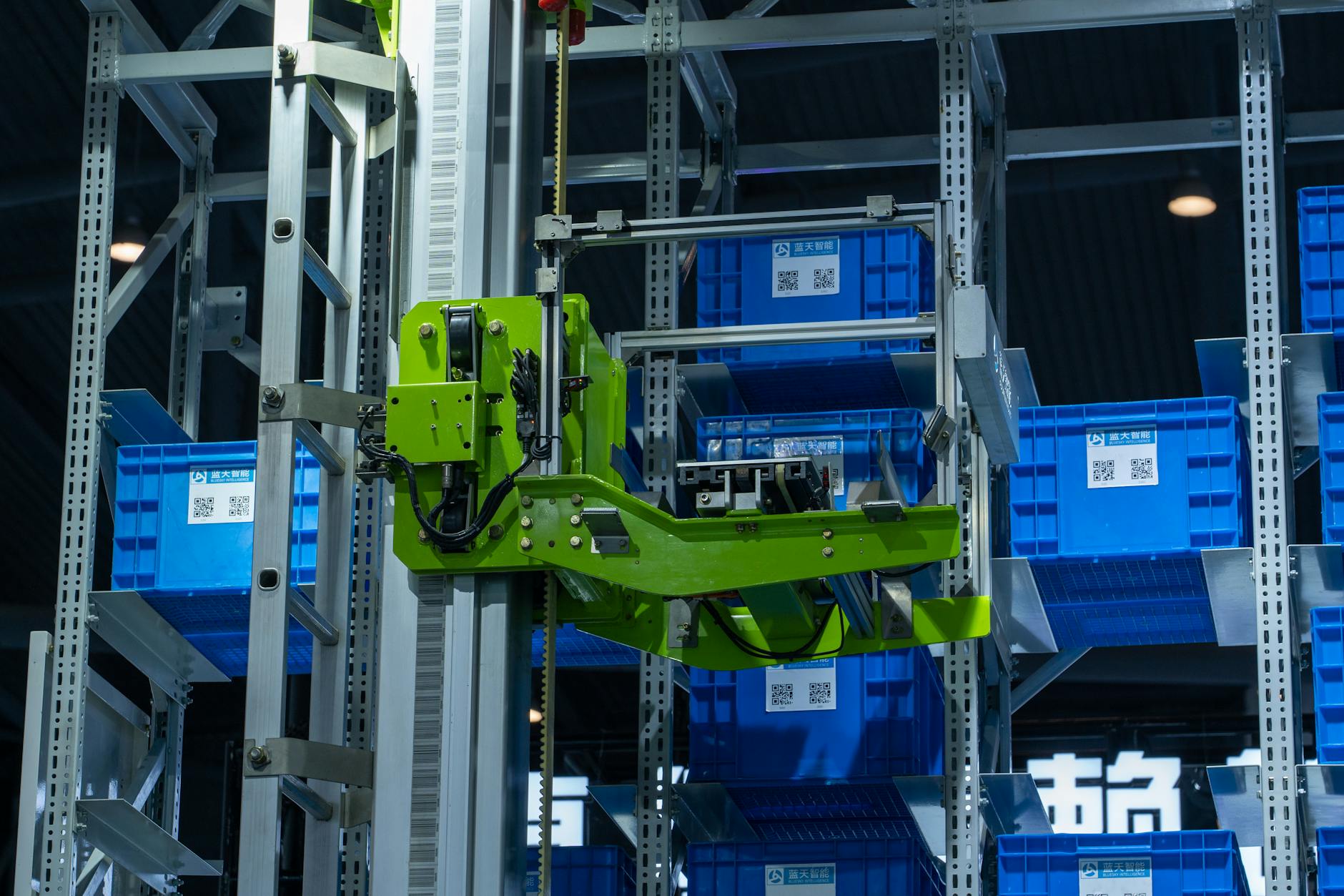 Jak technologie wizyjne i RFID poprawiają śledzenie przepływu towarów w pełni zautomatyzowanej logistyce Zielone ramię robota sortuje niebieskie skrzynki w zautomatyzowanym magazynie